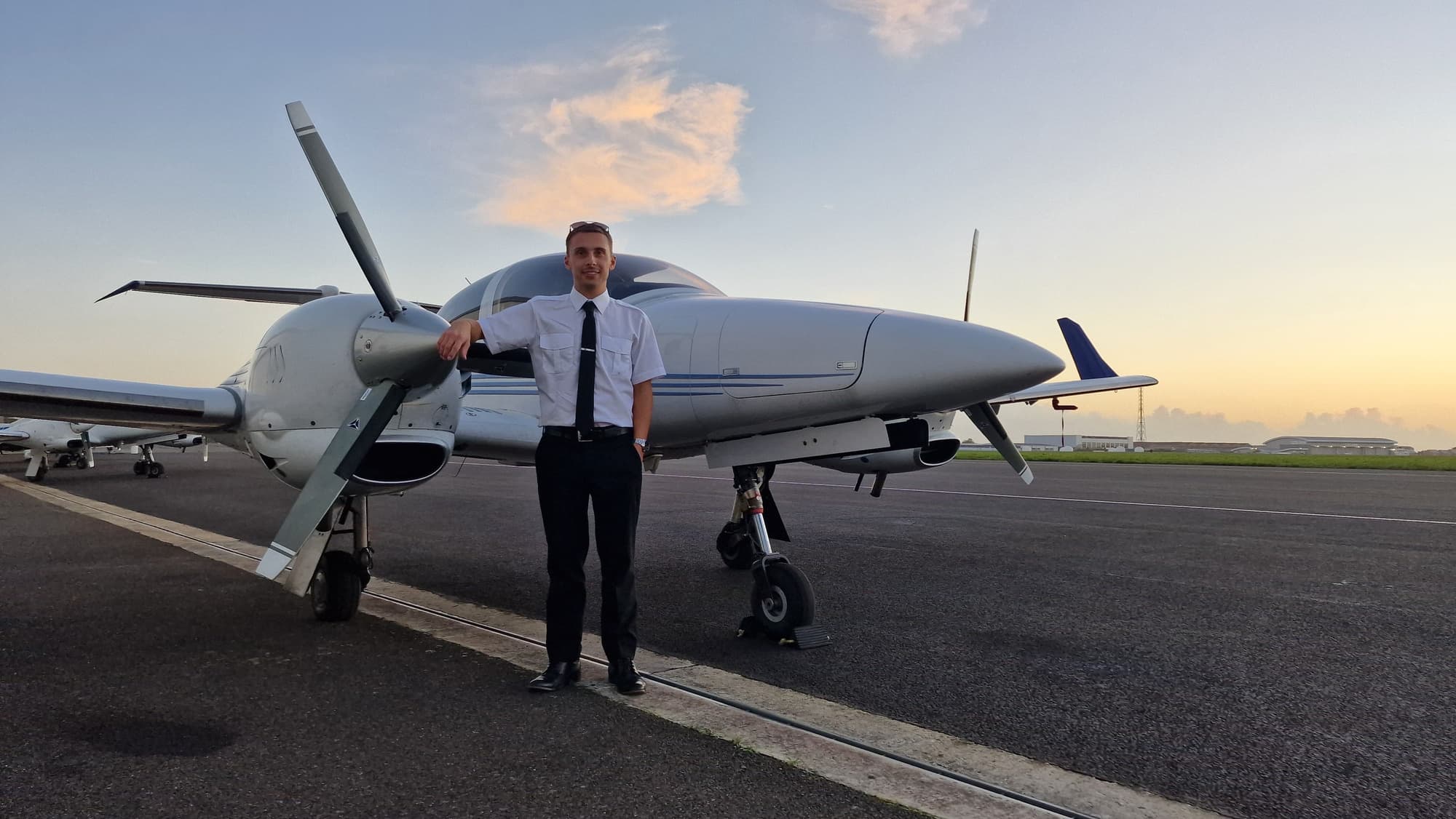 An EFT pilot standing beside a Diamond DA42 at sunset